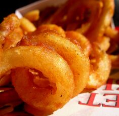 Curly fries are prepared with a special cutting tool that is either motor-driven or hand-turned (see an example of motorized curly fry machine.) The cutting implement is set into one end of the potato and the potato rotated, creating the spiral shapes as seen here. Curly fries are typically lightly coated with a flour and spice mixture of salt, paprika, black pepper, and other spices before frying, the result of which can be seen in this photo.